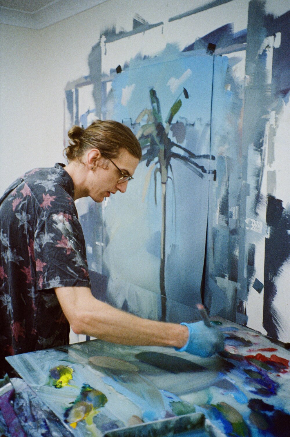 Dylan Jones holding paint brush in right hand and standing in front of a painting