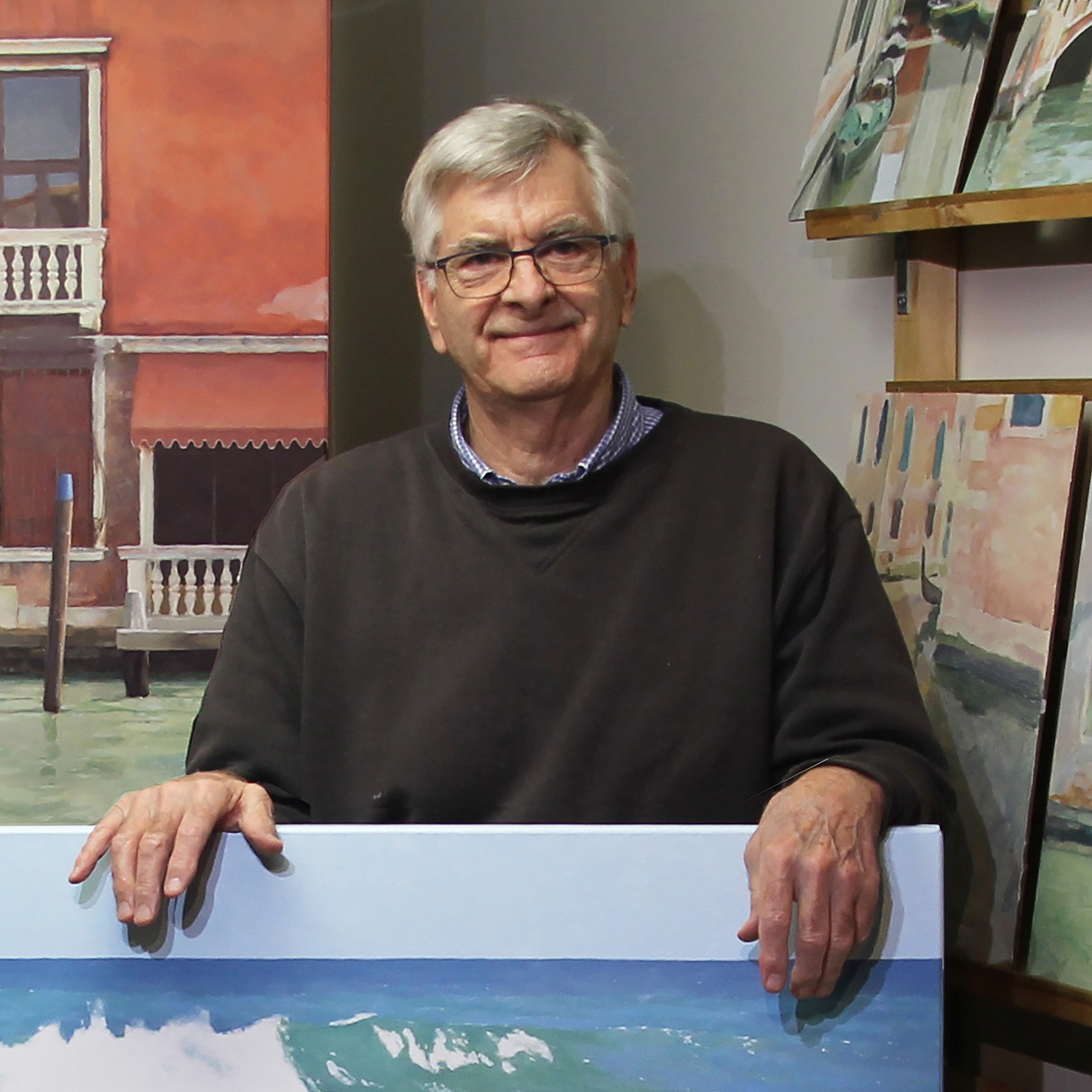 Rick Everingham looking at camera surrounded by his paintings