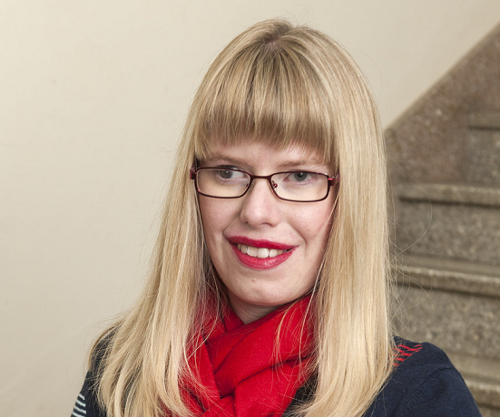 Profile photo of Jane Britt wearing black rimmed glasses and a red scarf with red lipstick